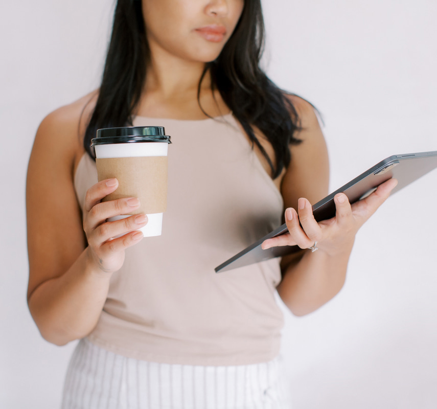 Woman holding a coffee and looking at tablet screen. How to avoid copyright infringement on social media